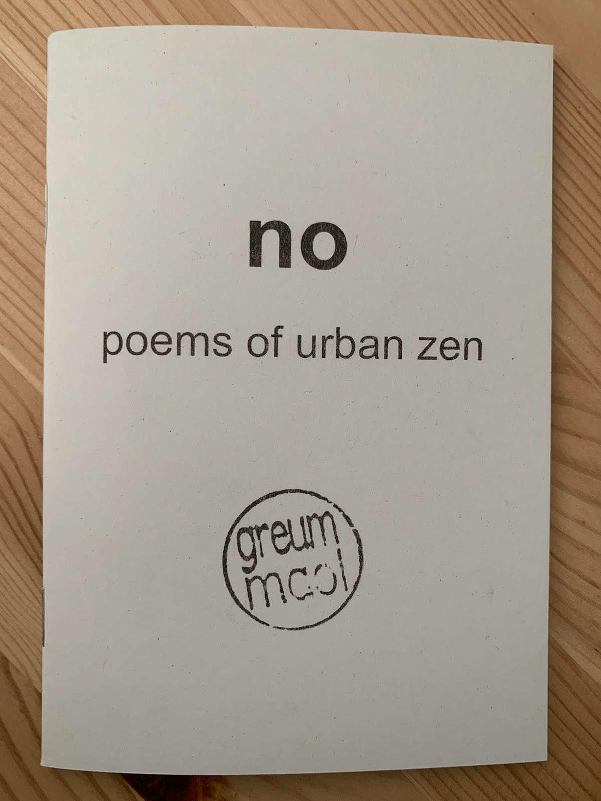 photograph of book. book cover art: off-white cover. centred a quarer down the page is the title 'no'. underneath is the subtitle 'poems of urban zen'. three quarters down the page is 'greum maul' inside a cirlce.