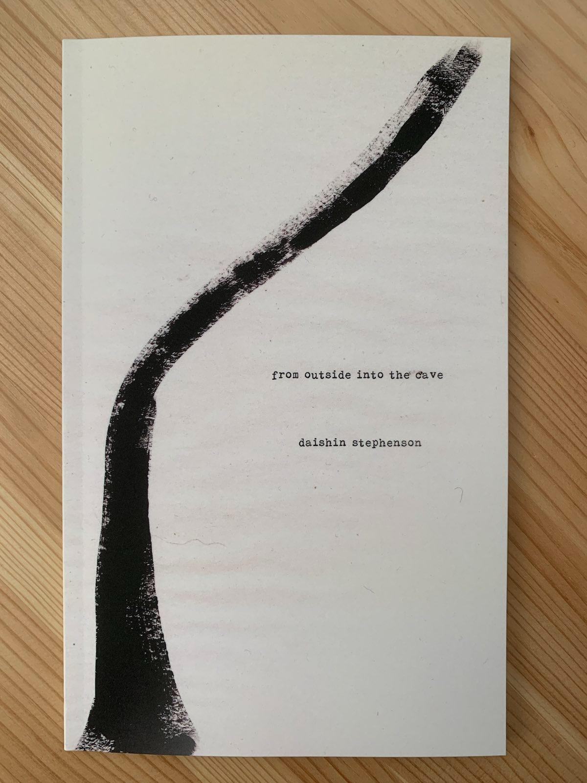 photograph of book. book cover art: off-white background. painting of branchless tree trunk. middle of the cover sits the title 'from outside into the cave'. an inch or so below the title is the author's name, daishin stephenson.